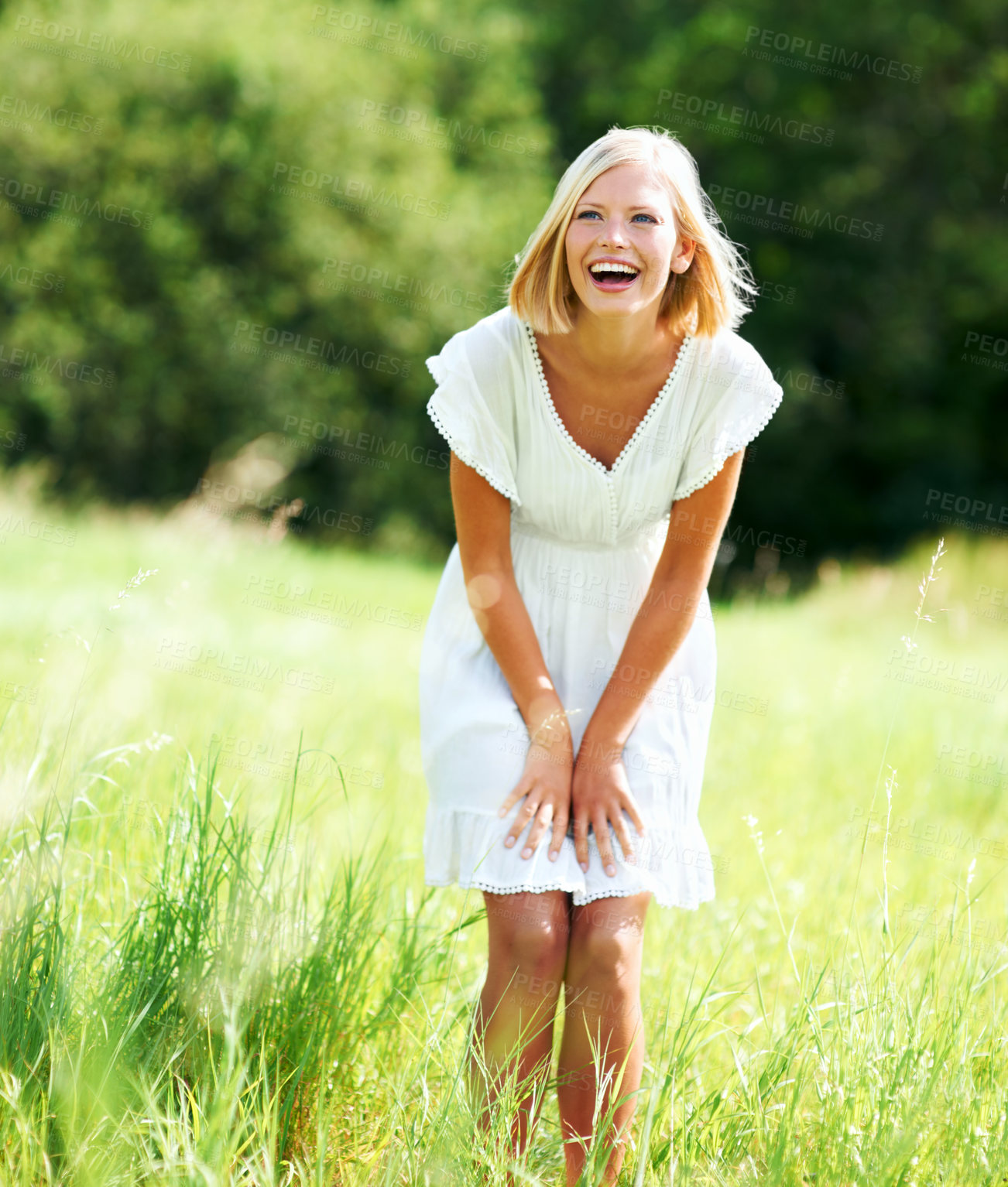 Buy stock photo Cute young woman laughing while standing in a field outdoors