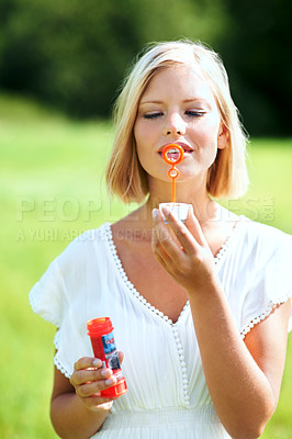 Buy stock photo Woman, portrait and blowing bubbles in nature for fun day in sunshine at outdoor park. Face of young happy female person or blonde with stick or wand to blow bubble on playful holiday or summer break