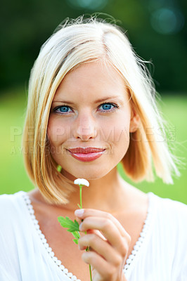 Buy stock photo Gorgeous young woman holding a tiny flower outdoors