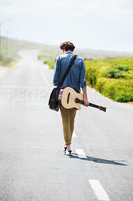 Buy stock photo Musician, walking and man with a guitar on a road trip, journey or tour in the countryside on highway. Guitarist, travel or back of guy trekking on street or asphalt in a green and rural landscape