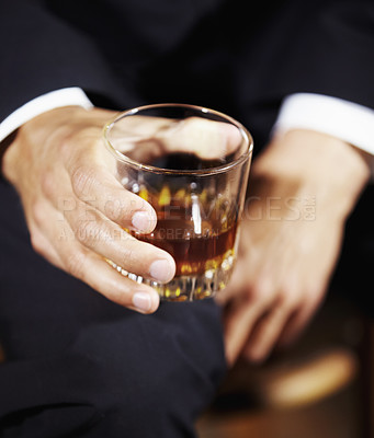 Buy stock photo Closeup of a man holding whiskey in a glass against a dark copyspace background. Zoom in on a rich alcoholic gentleman's drink, had in celebration, success or power. The taste of class and wealth 