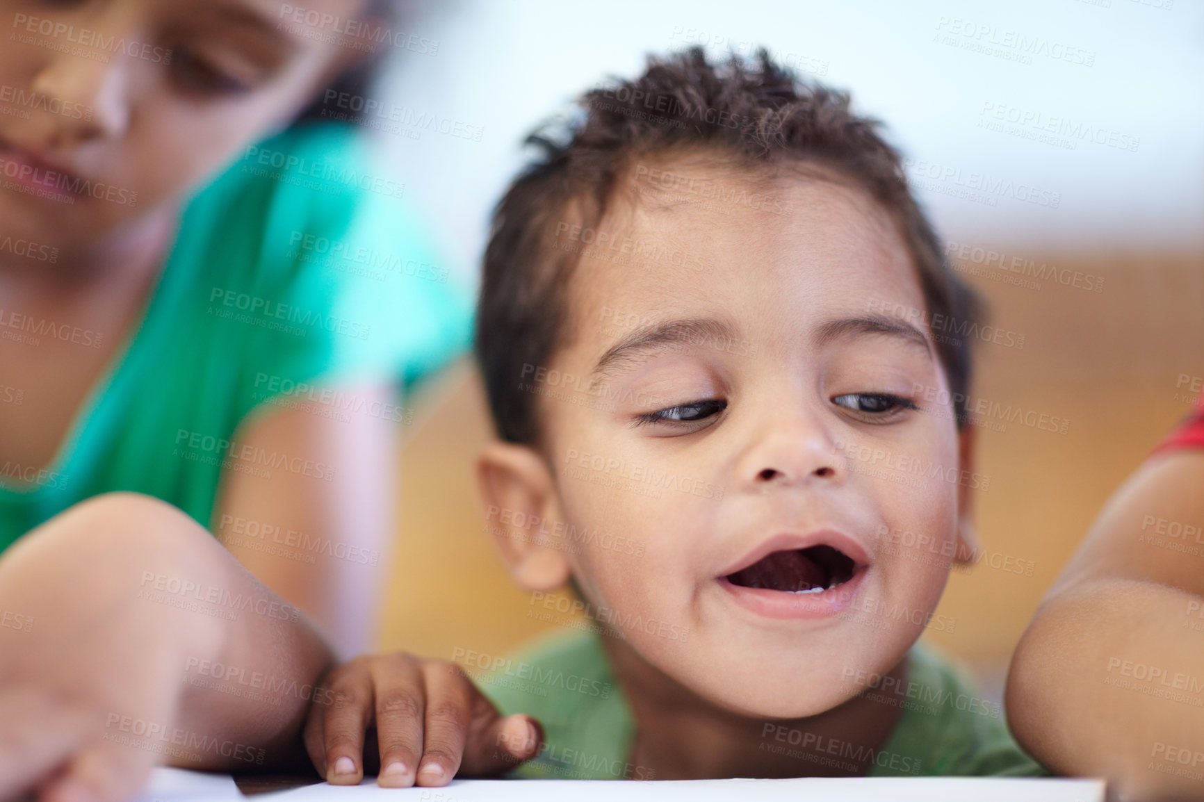 Buy stock photo Cute little boy looking at a drawing while at a table