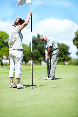 Buy stock photo Woman with flag, old man or golfer on golf course for a birdie, putting stroke or exercise in retirement. Senior couple, mature or serious player training in golfing sports game driving with a club