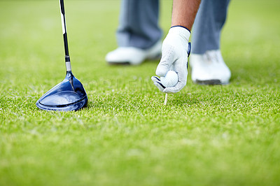 Buy stock photo A male golfer placing his golf ball and tee in the ground