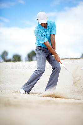 Buy stock photo An image of a young male golfer chipping his ball out of a bunker in a game of golf