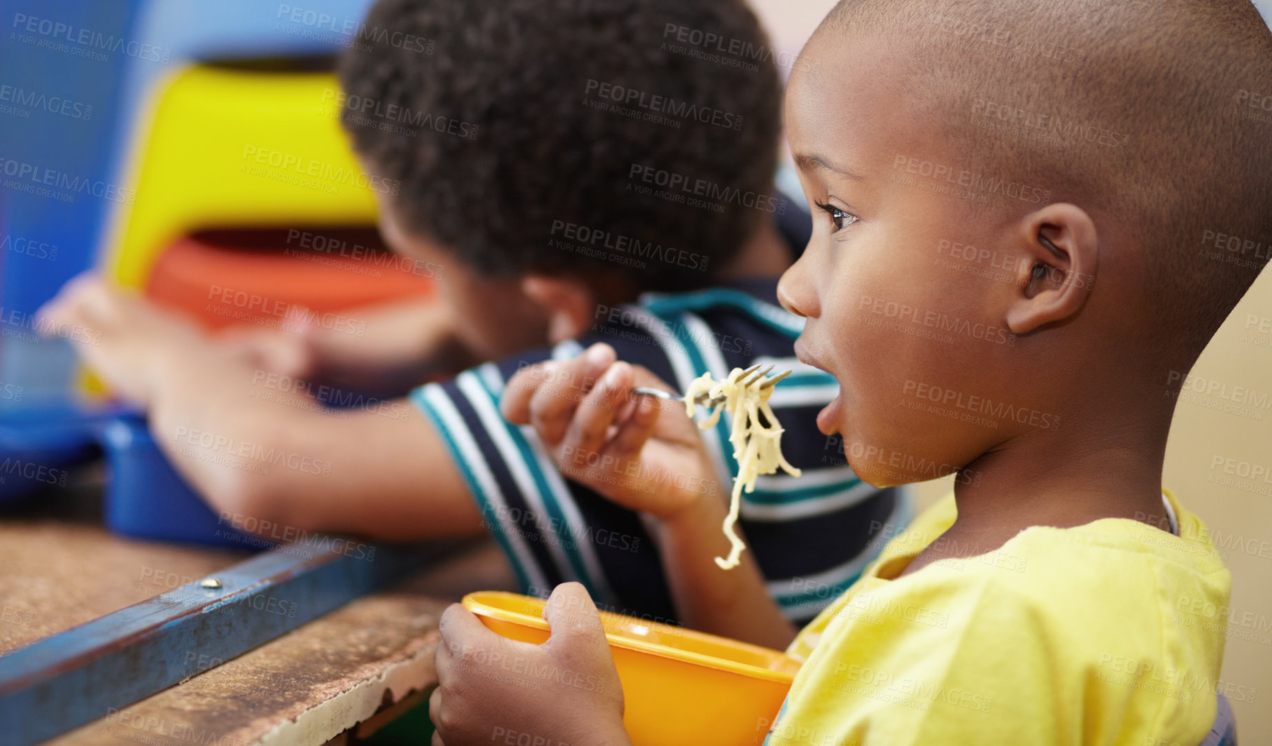 Buy stock photo Child, lunch and eating in school, kindergarten or classroom and healthy nutrition, food and noodles. Kids, black boy and hungry kid or eat snack, pasta in lunchbox or breakfast in kindergarden