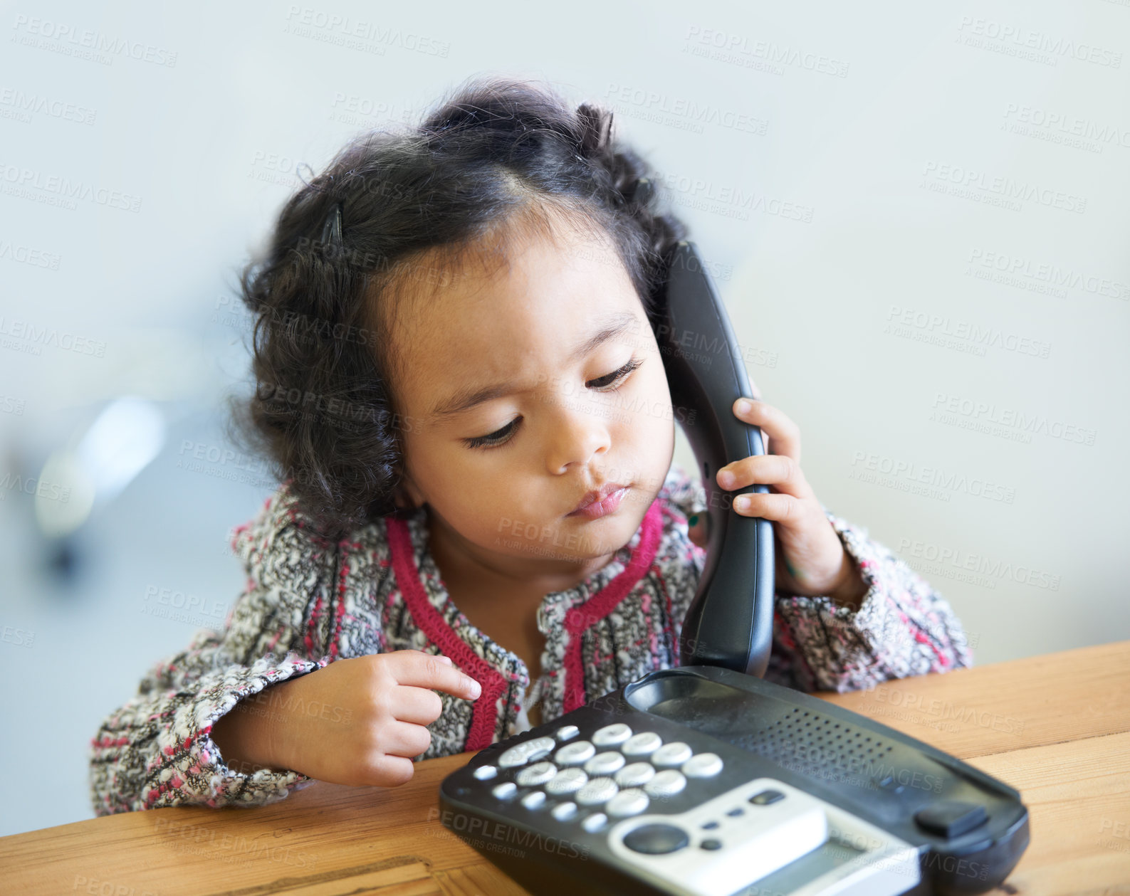 Buy stock photo Playing, serious and a child on a telephone phone call for communication in a house. Home, contact and a girl, kid or baby listening on a landline for conversation, play or a discussion at a desk