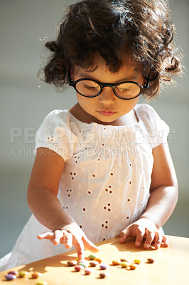 Buy stock photo Shot of a little girl at home alone with pills on the table in front of her