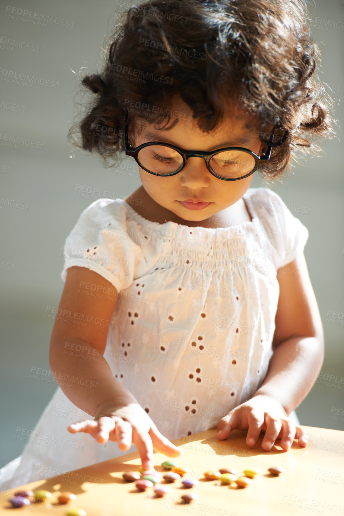 Buy stock photo Shot of a little girl at home alone with pills on the table in front of her