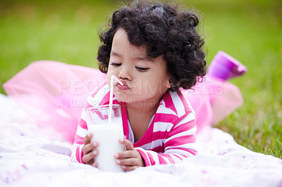 Buy stock photo Kid, girl and lying on grass with milk for drinking by straw in pink tutu, princess or dress up. Child, youth and curly hair with calcium for development, growth and strong bones with healthy diet