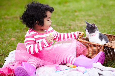Buy stock photo Food, picnic and a girl in the park with her kitten together for love, care or bonding during summer. Chips, cat and kids with a happy young child feeding her pet animal a snack in the garden