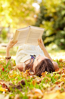 Buy stock photo Reading, book and woman relax in park with novel in nature learning for education as student outdoor on campus. University, college and young person with textbook on grass field for scholarship