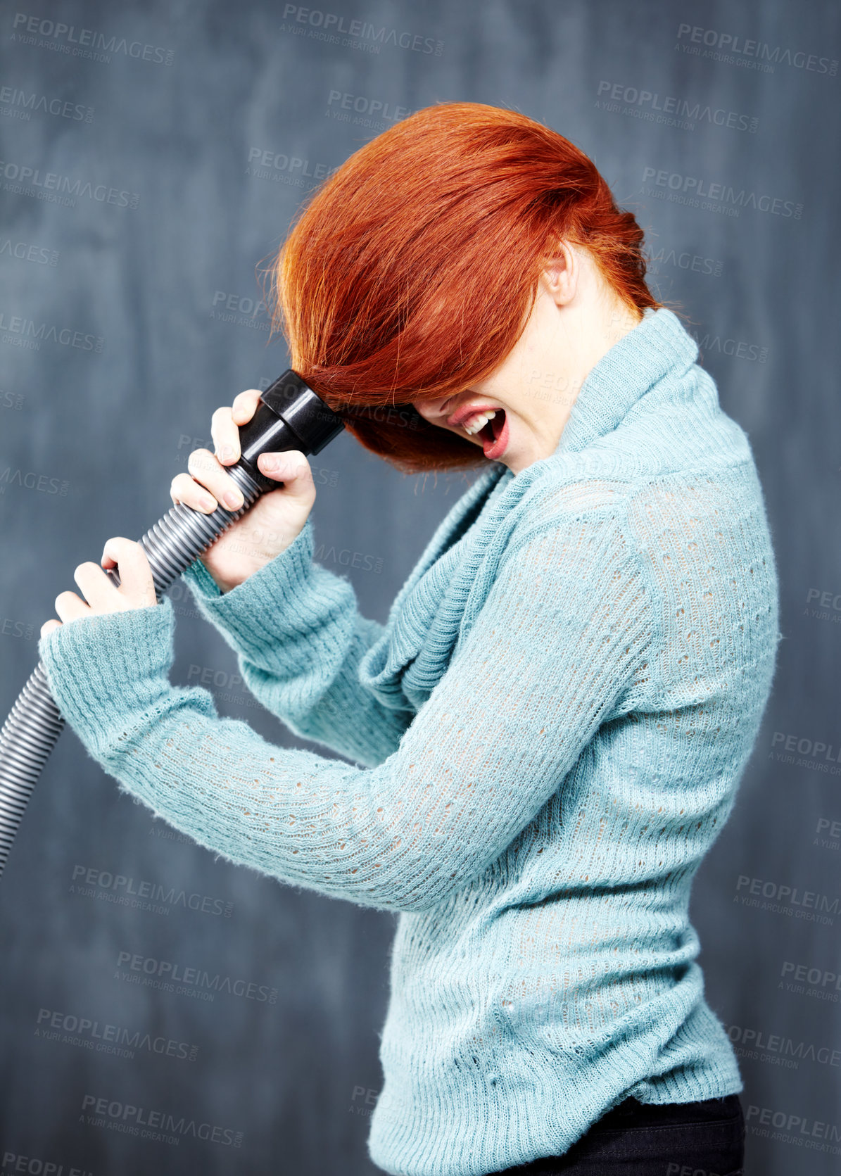 Buy stock photo A young redhead with her hair stuck in the vacuum cleaner