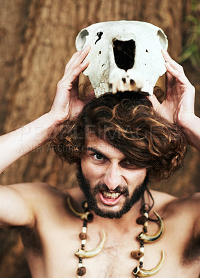 Buy stock photo An aggressive caveman placing an animal skull on his head