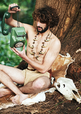 Buy stock photo Caveman, forest and modern artifact holding a phone feeling curious outdoor in the woods. Bone necklace, wilderness and first man with technology and communication discovery of a person in nature