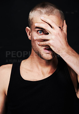 Buy stock photo Portrait, anxiety and man peek through hands in studio isolated on a black background. Face, scared and person peep through fingers, spy or paranoid at horror, fear danger or stress for mental health