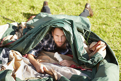 Buy stock photo Frustrated young man struggling to erect a tent outdoors