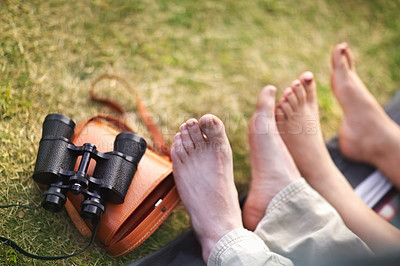 Buy stock photo Binoculars, hiking and the feet of a couple on the grass closeup for travel, relax or adventure in nature. Camping, love or romance with a man and woman outdoor in the forest together from above