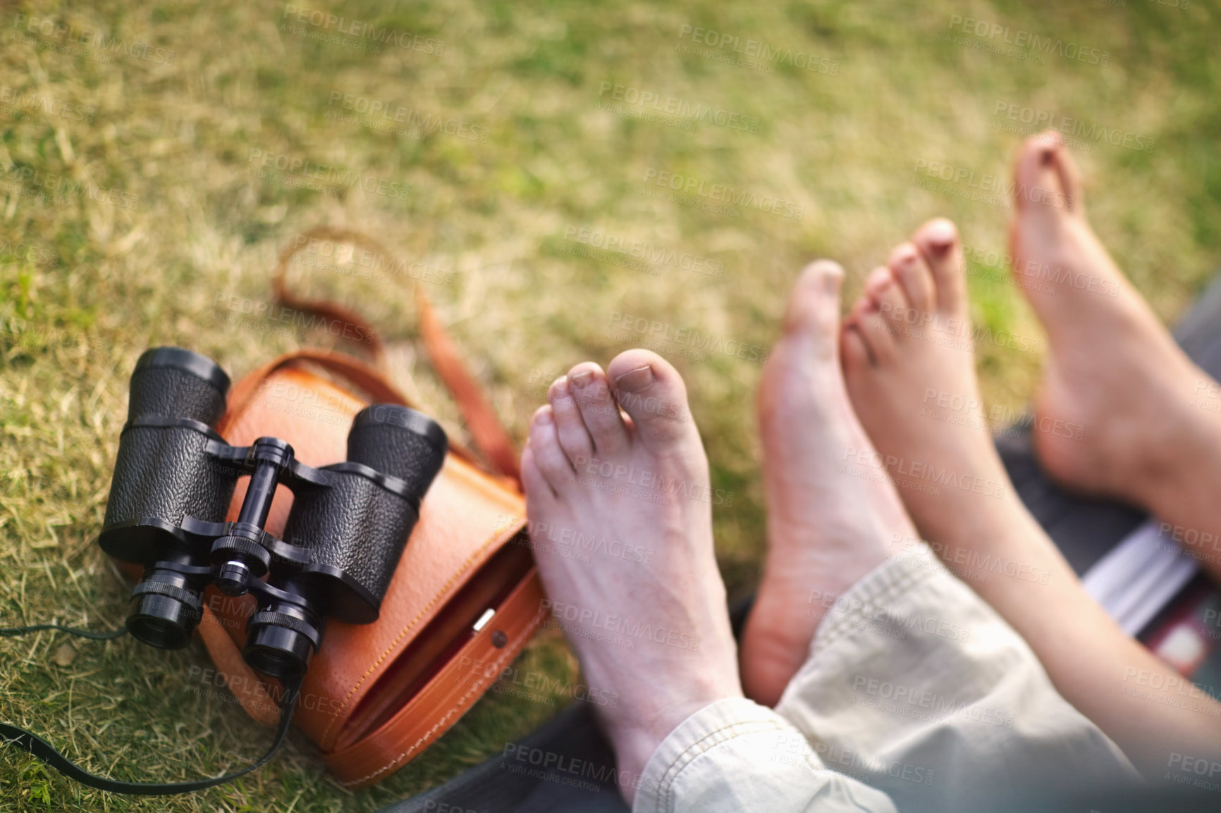 Buy stock photo Binoculars, hiking and the feet of a couple on the grass closeup for travel, relax or adventure in nature. Camping, love or romance with a man and woman outdoor in the forest together from above