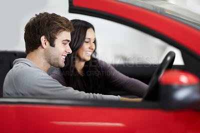 Buy stock photo Attractive young couple trying out new cars at a dealership