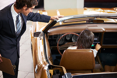 Buy stock photo Handsome young classic car salesman standing in the dealership and helping a client make a decision