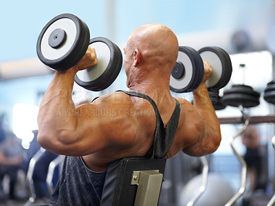 Buy stock photo Shot of a male bodybuilder lifting weights at the gym