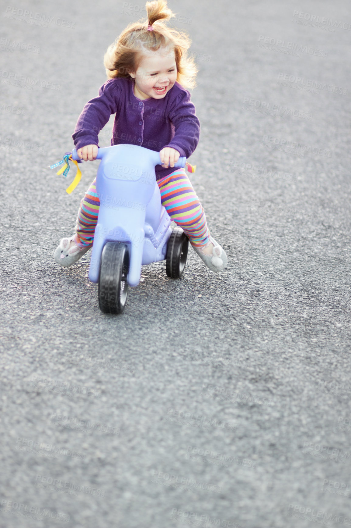 Buy stock photo A cute baby girl riding her tricycle outside on the street