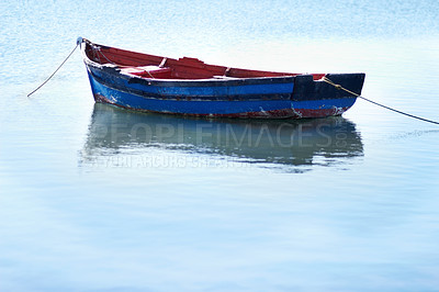 Buy stock photo Shot of an empty fishing boat floating on calm waters