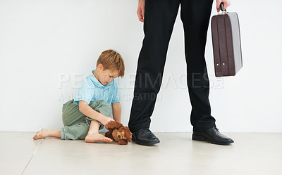 Buy stock photo A young boy holding a teddybear and looking sad because his dad has to go to work