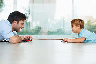 Buy stock photo A cute boy and his young father playing with toy cars on the floor