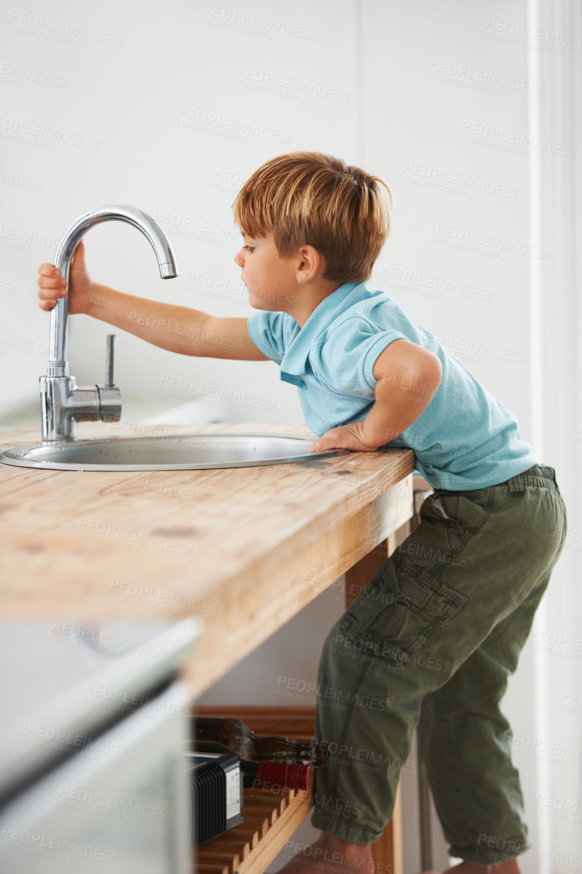 Buy stock photo Kids, fantasy and a boy in the kitchen sink, playing a game in his home as a plumber character. Children, basin and counter with a young male kid in a modern apartment for imaginary plumbing