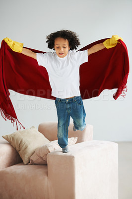 Buy stock photo Fly, children and a boy superhero in a costume on a sofa in the living room of his home for playing a game. Jumping, growth and fantasy with a young kid in a cape for justice or safety cosplay