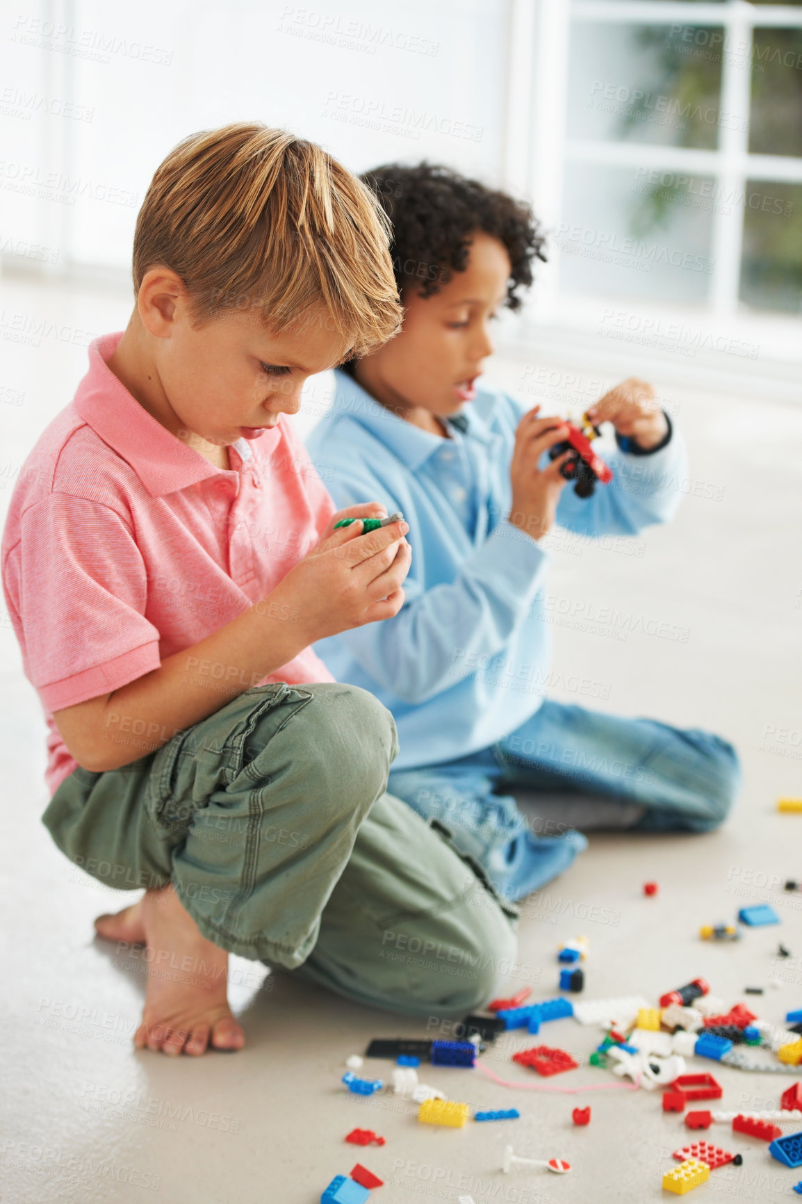 Buy stock photo Two cute young boys playing with building blocks on the flor