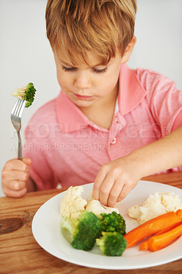 Buy stock photo A cute young boy playing with the vegetables on his plate