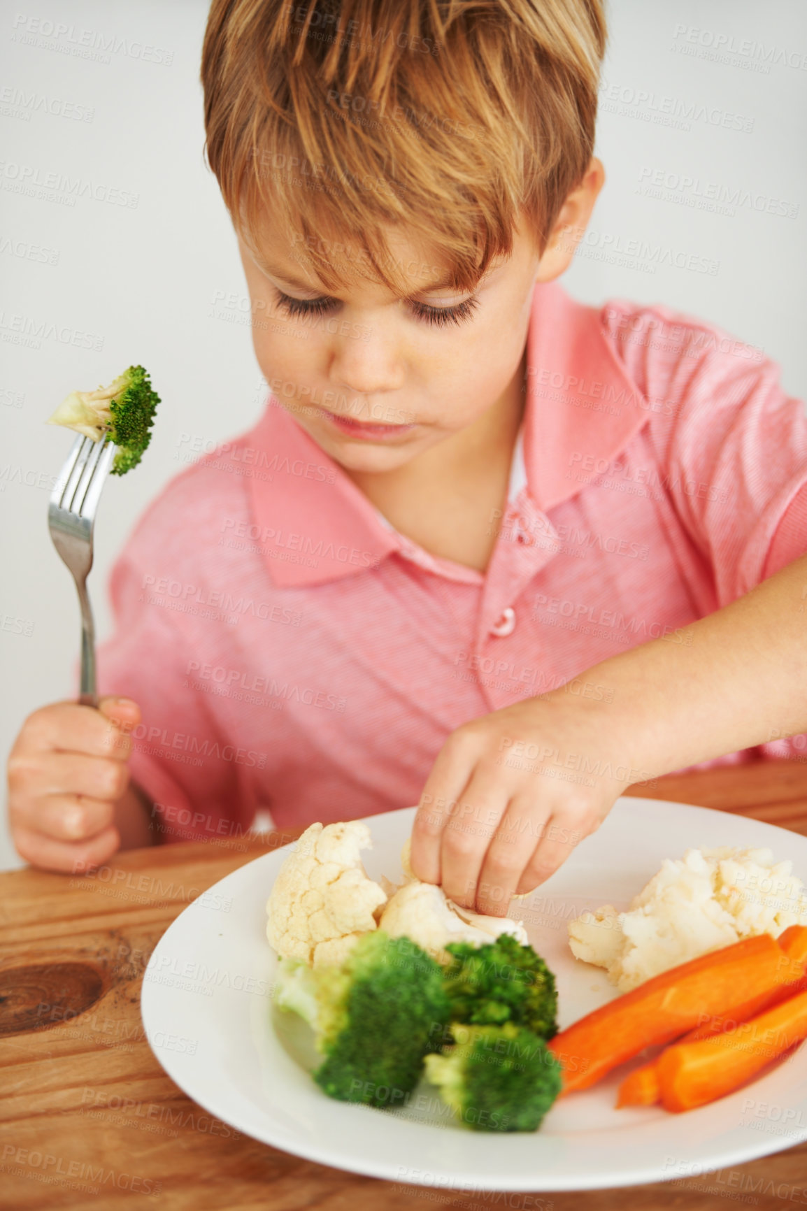 Buy stock photo A cute young boy playing with the vegetables on his plate
