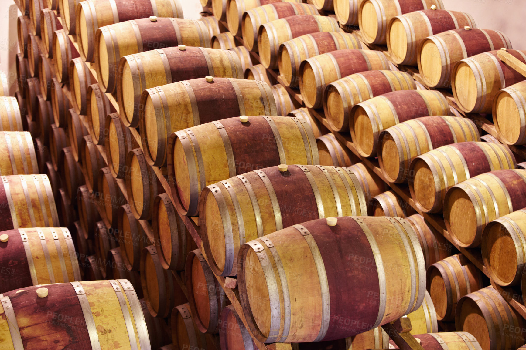 Buy stock photo Wine barrels stacked in an old cellar of the winery. Fine red wine stored in wooden containers in a wine cellar. Long rows of oak barrels for maturing red wine. Wine production in a warehouse