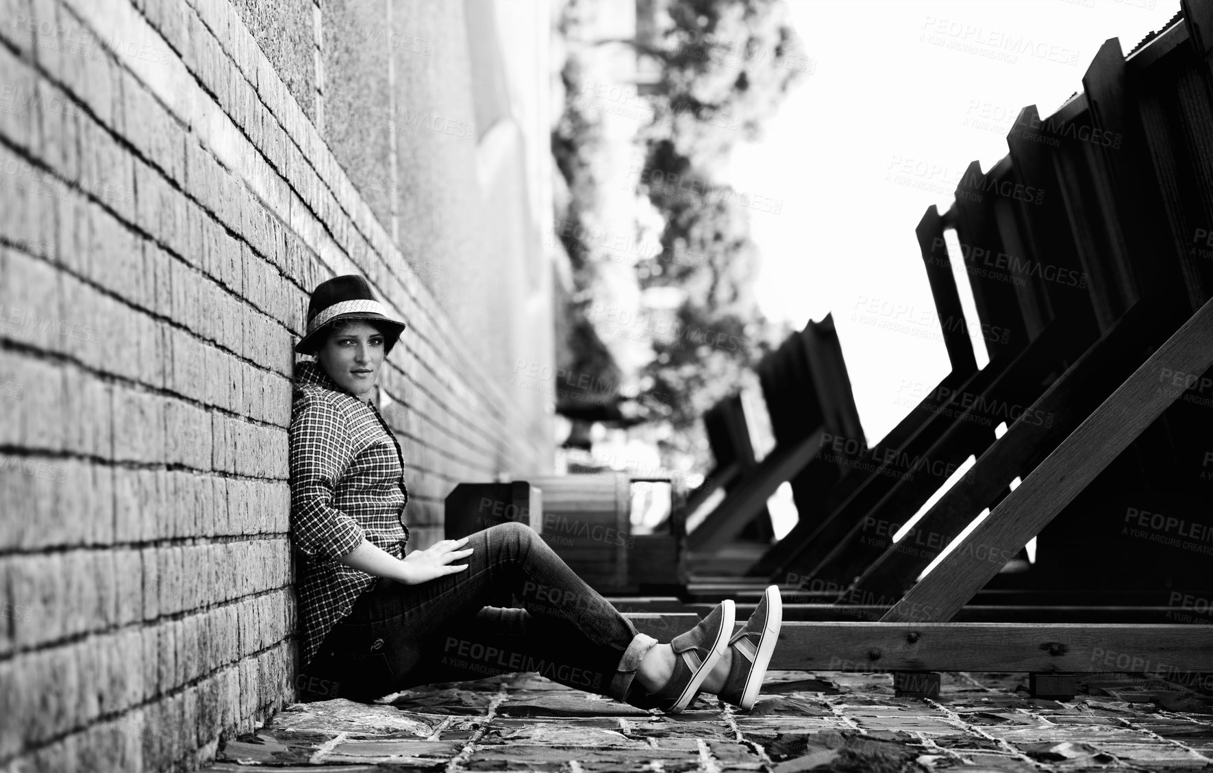 Buy stock photo A woman appears to be sitting on the side of a building with her back against the sidewalk - perspective