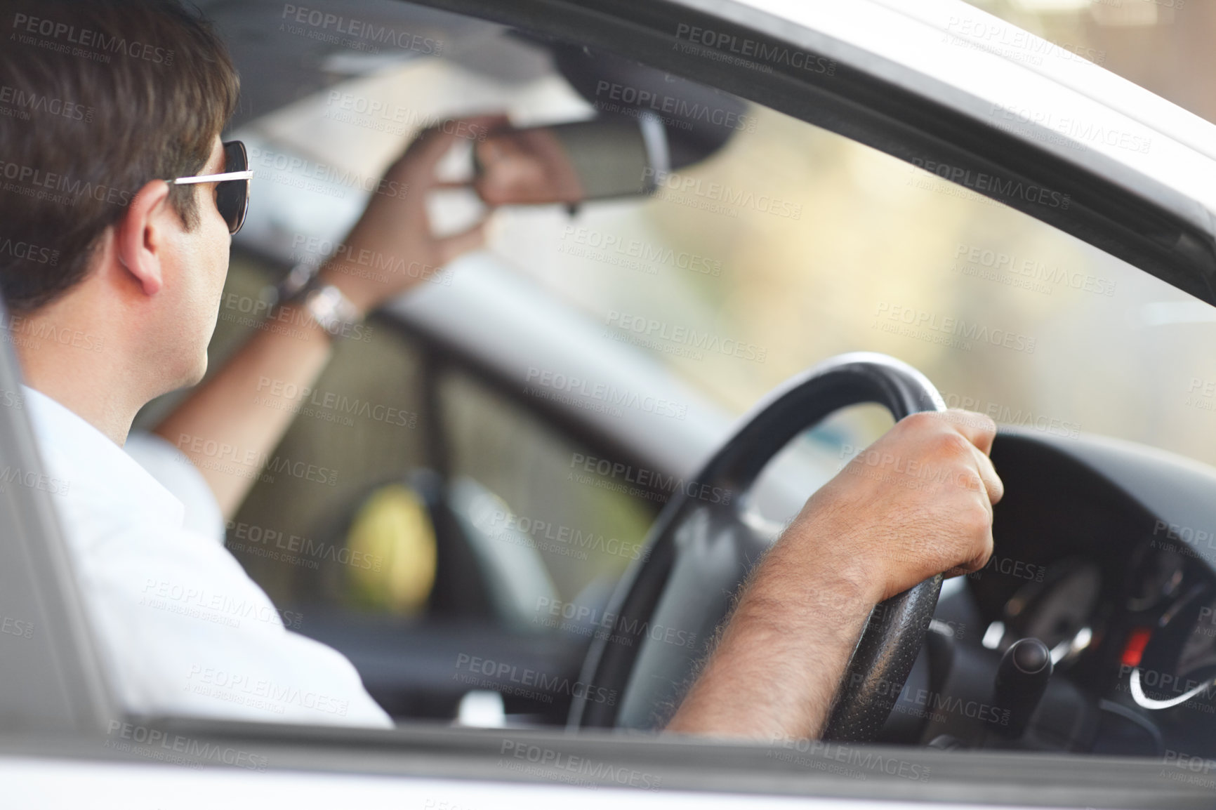 Buy stock photo A man adjusting his rear view mirror while driving