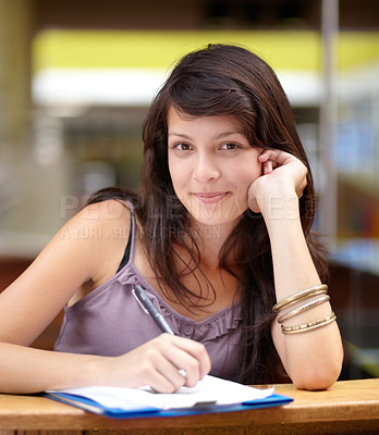 Buy stock photo A young attractive Indian woman taking notes in class
