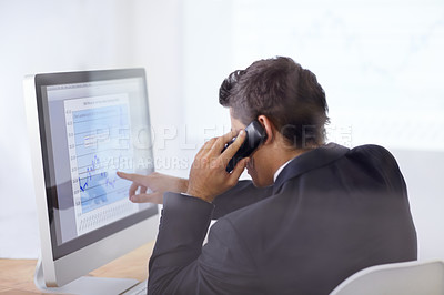Buy stock photo Shot of a businessman talking on the phone and pointing at a graph on his computer screen