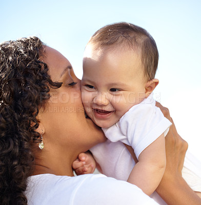 Buy stock photo Closeup of a young mother holding up and kissing her baby daughter