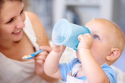 Buy stock photo A young mother watching her baby boy drink from his sippy cup
