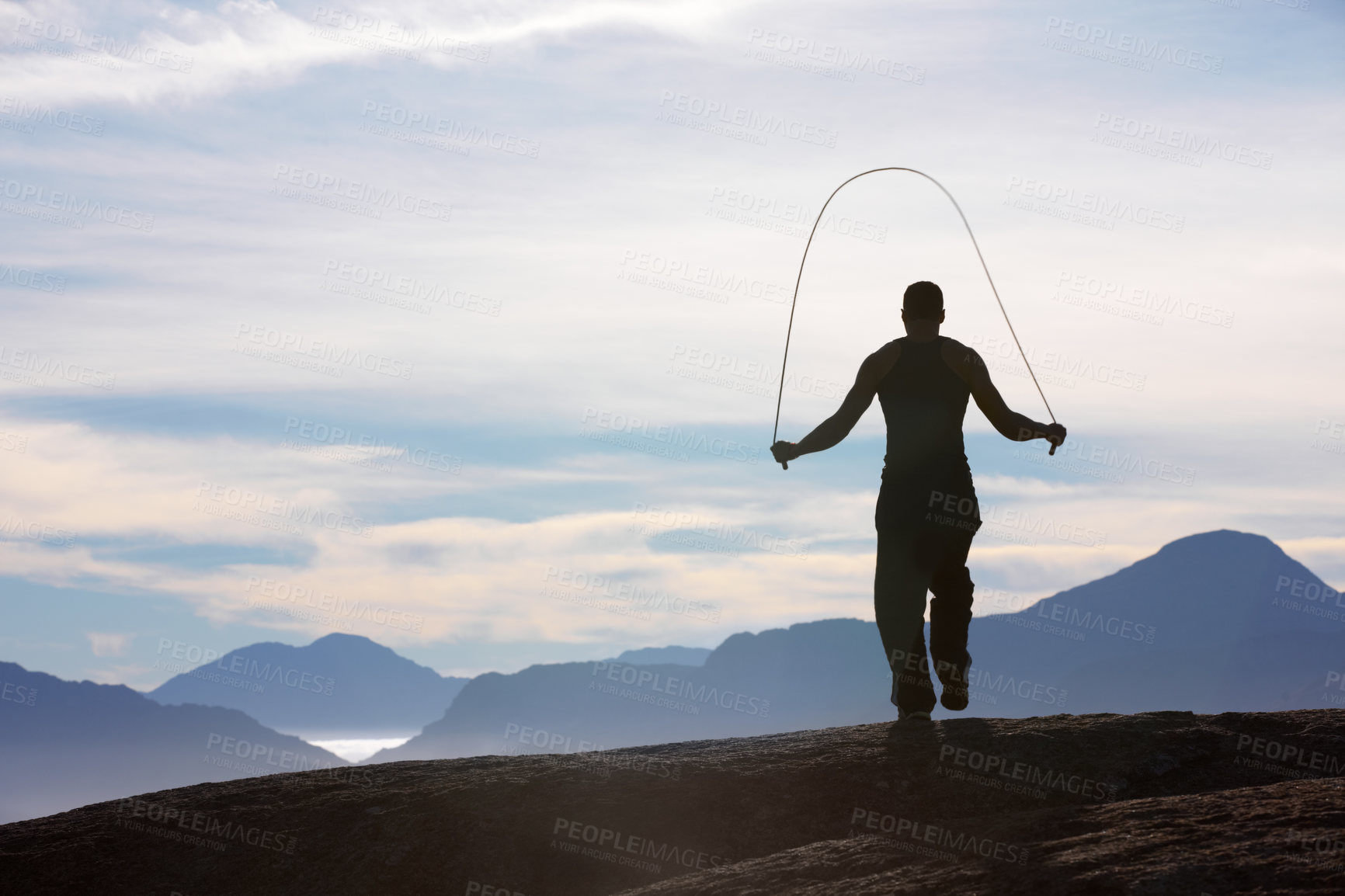 Buy stock photo Rearview of a man skipping on a mountain top