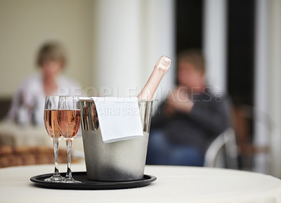 Buy stock photo A champagne bottle and two champagne glasses on a restaurant table