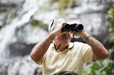 Buy stock photo Shot of a senior man looking at scenery with a pair of binoculars
