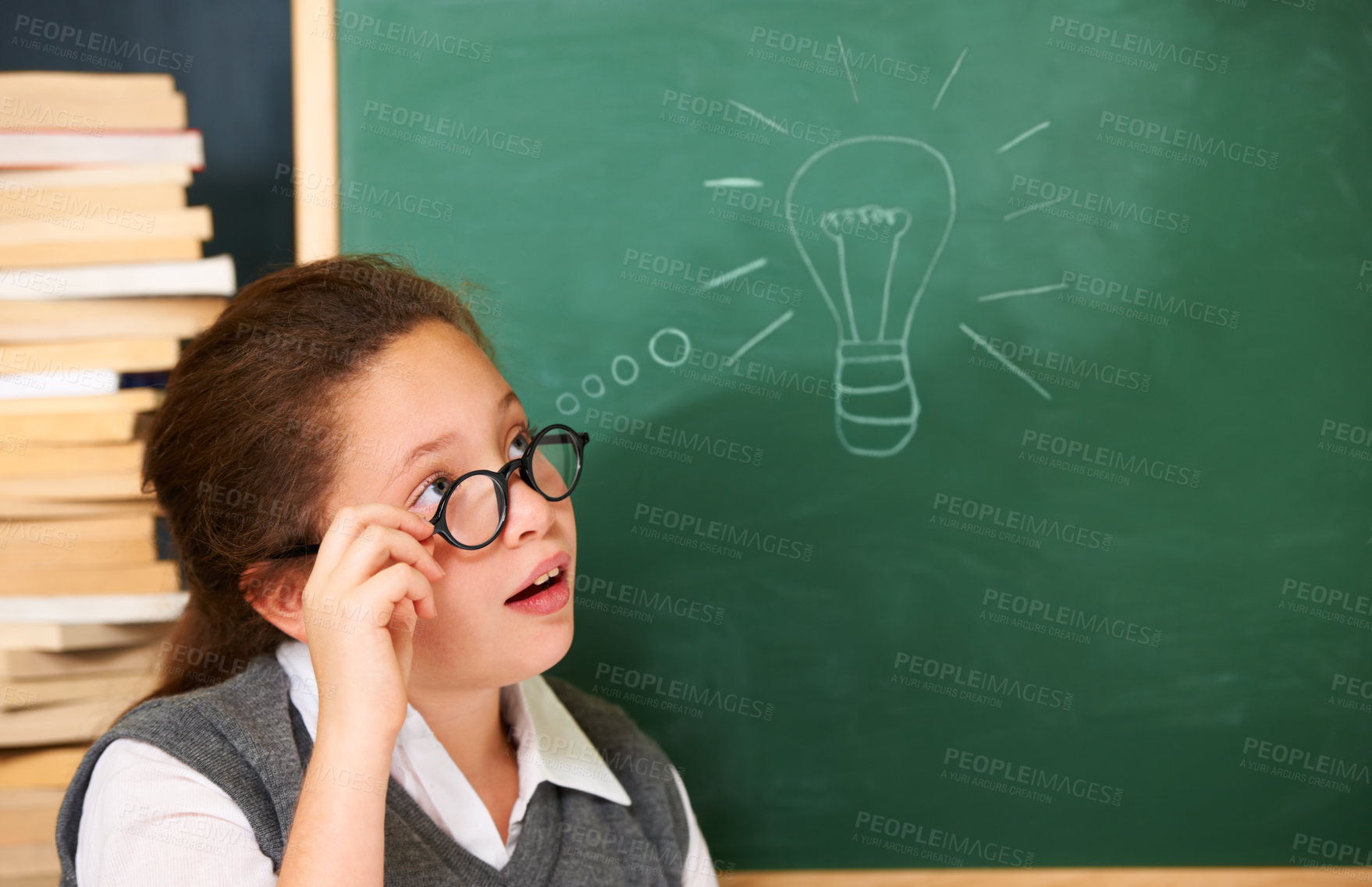 Buy stock photo Thinking, idea and student with light bulb on board for planning, decision or brainstorming in classroom. Education, learning and girl child with drawing for choice, vision or future in school.