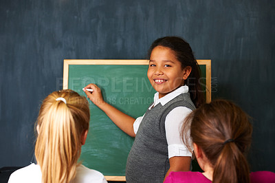 Buy stock photo Portrait of a cute girl showing her two friends something on the chalkboard in class