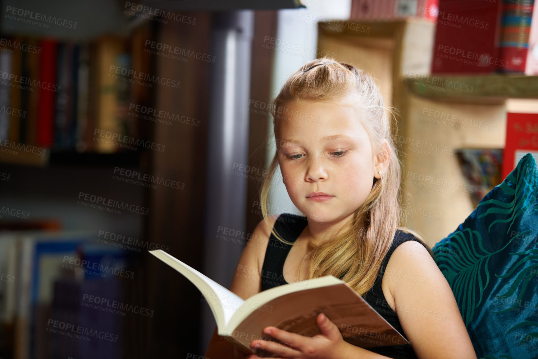 Buy stock photo Girl, kid and library for reading book, education and learning of language, literature and fiction story on sofa. Child relax in bookstore with novel for creative development, knowledge and school