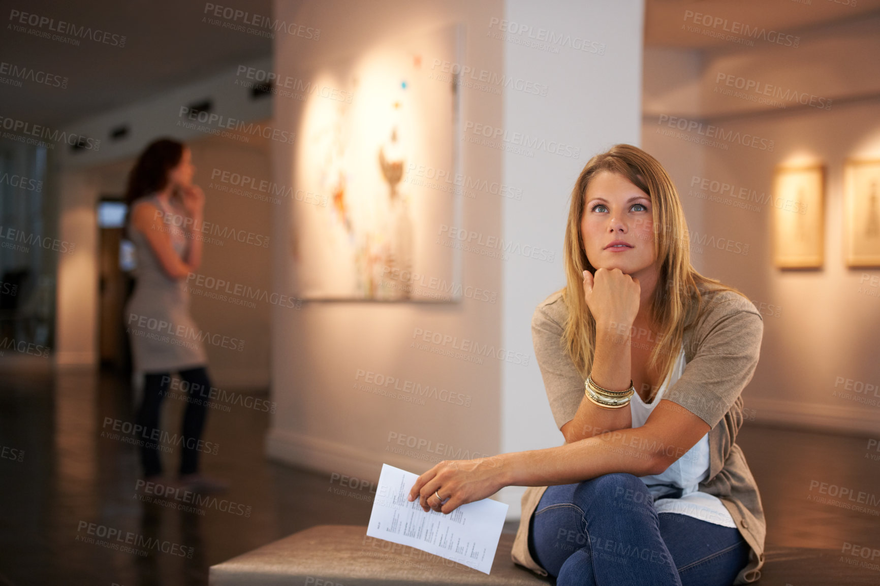 Buy stock photo Two young friends looking at paintings while attending an exhibition