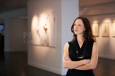Buy stock photo Shot of a young woman looking at paintings in a gallery